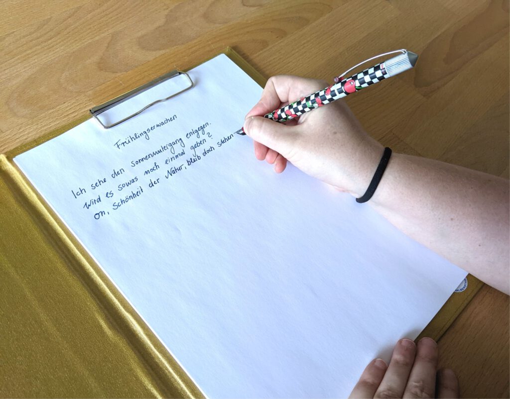 Jemand schreibt etwas auf ein Blatt Papier.